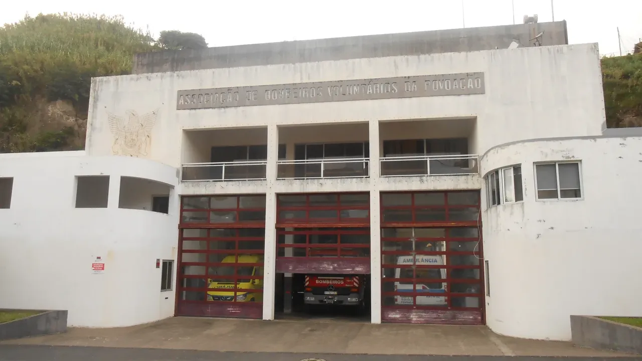 Quartel de bombeiros voluntários na Povoação, São Miguel, com ambulâncias e um carro de bombeiros estacionados nos portões abertos